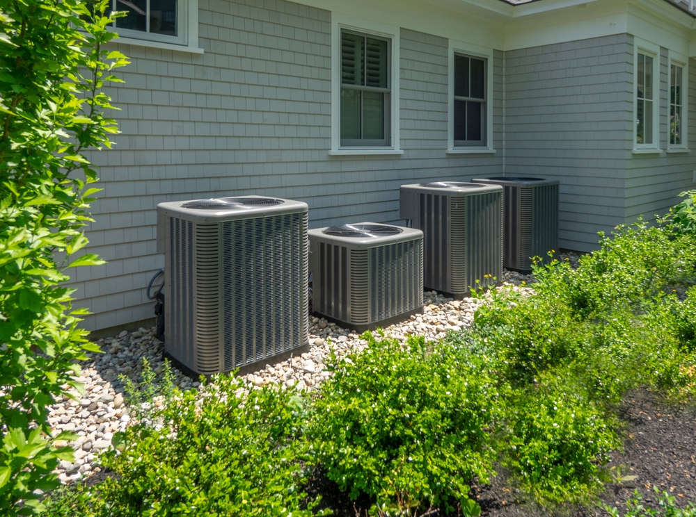 Four outdoor air conditioning units beside a house