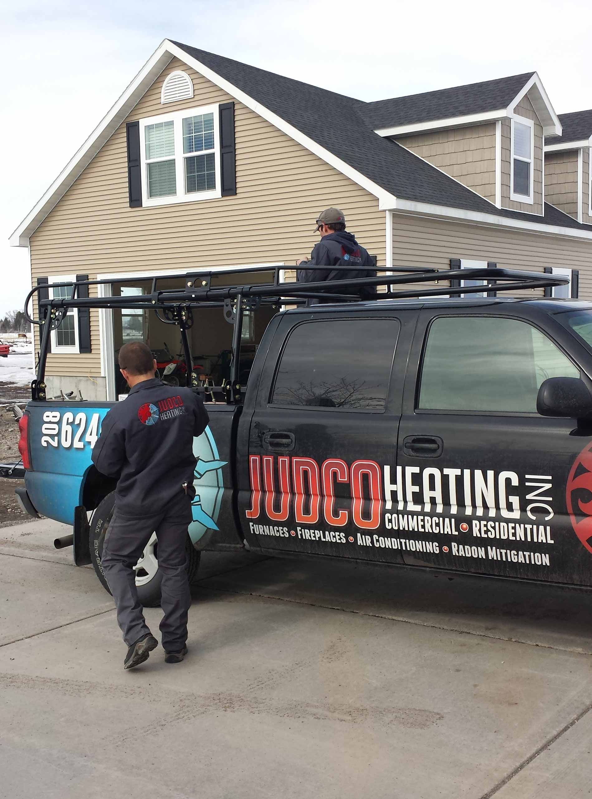 Workers beside a Judco Heating truck outside a house
